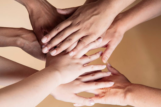 Hands Of Every Skin Tone And Type Reach In Toward A Center Where They Stack Atop Each Other